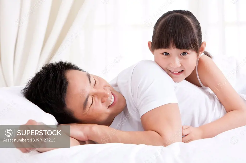 Father and daughter having fun in bed