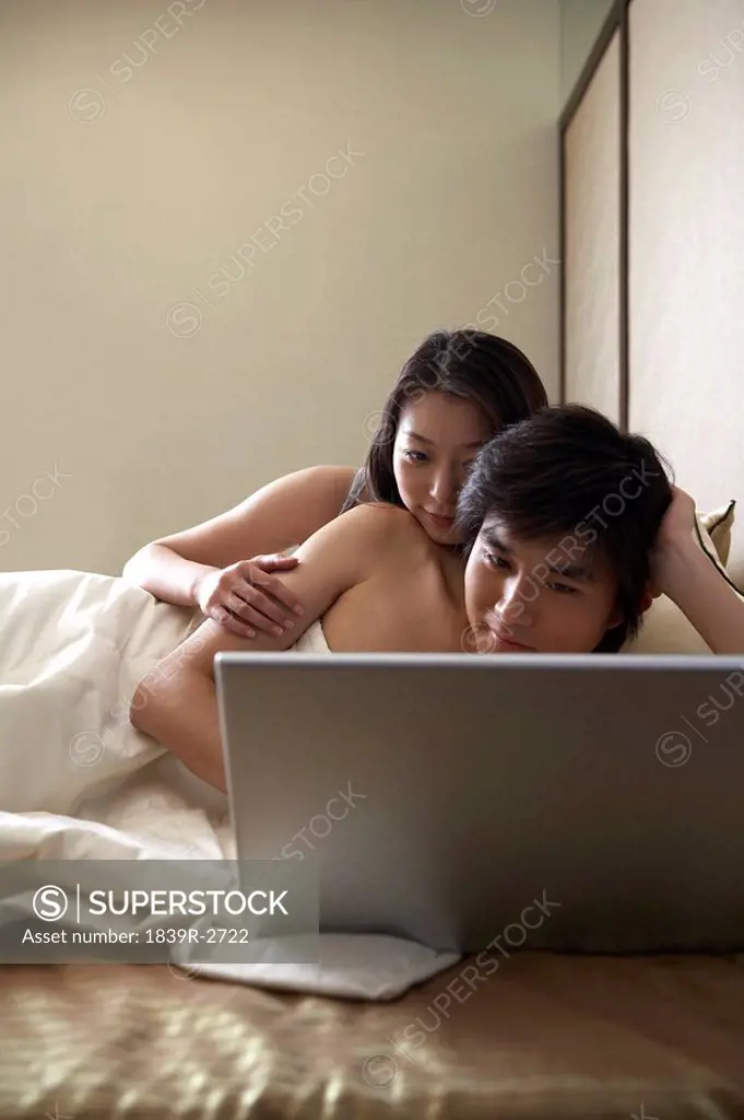 Young Couple In Bed With A Laptop Computer