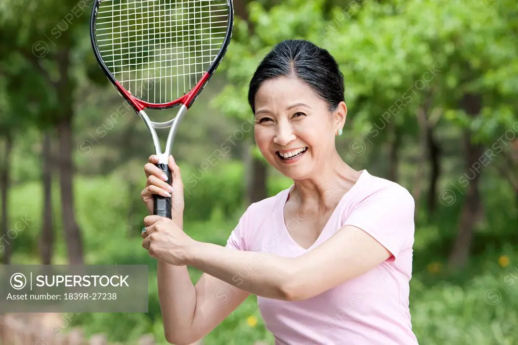 Senior woman playing tennis in park