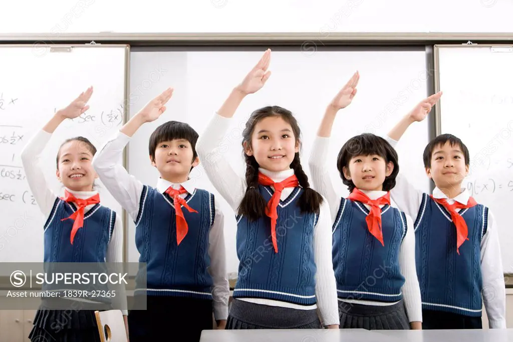 Young students saluting in a row at school