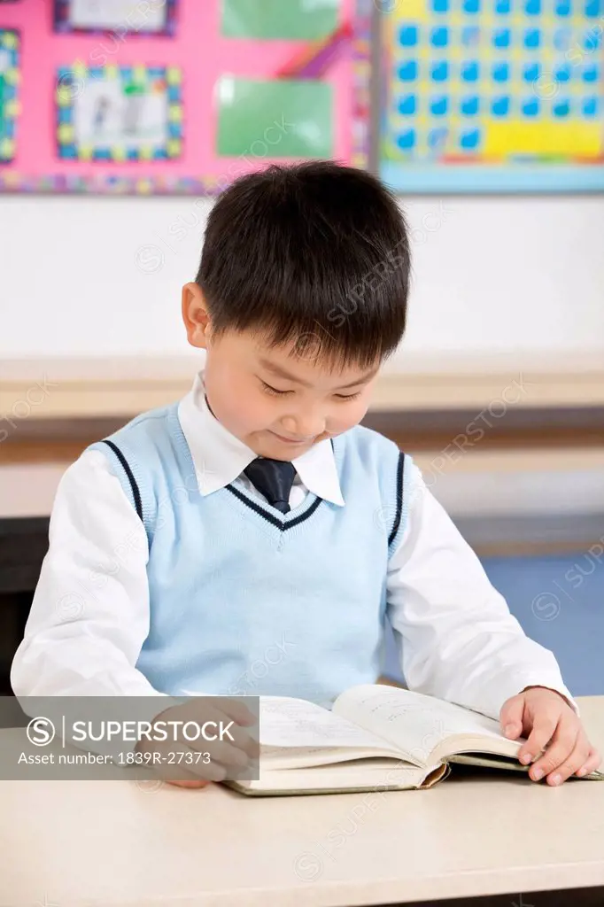 Young boy reading at his desk in a classroom