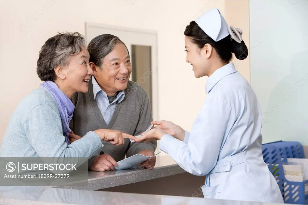 Young Nurse Helping Senior Couple at Nurses´ Station