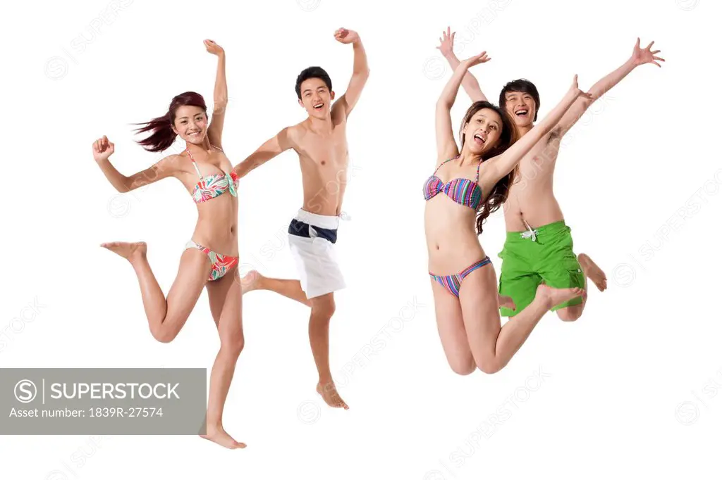 Young men and young women in swimsuit jumping in mid_air