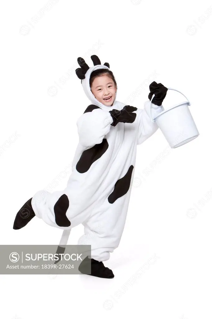 Cute girl in a cow costume with a bucket