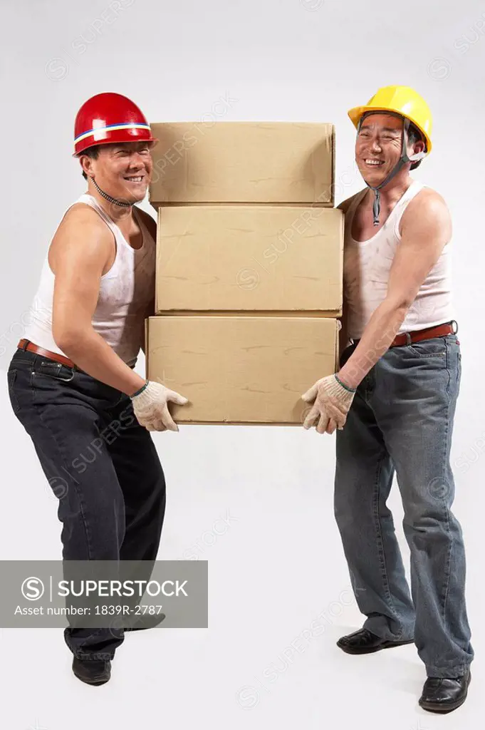 Men Wearing Hard Hats Lifting A Large Box