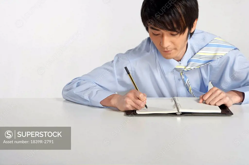 Young Man Writing In A Notebook