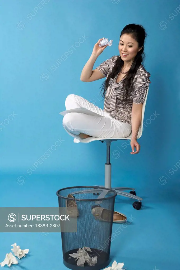 Woman Sitting On Chair, Throwing Paper Into Bin