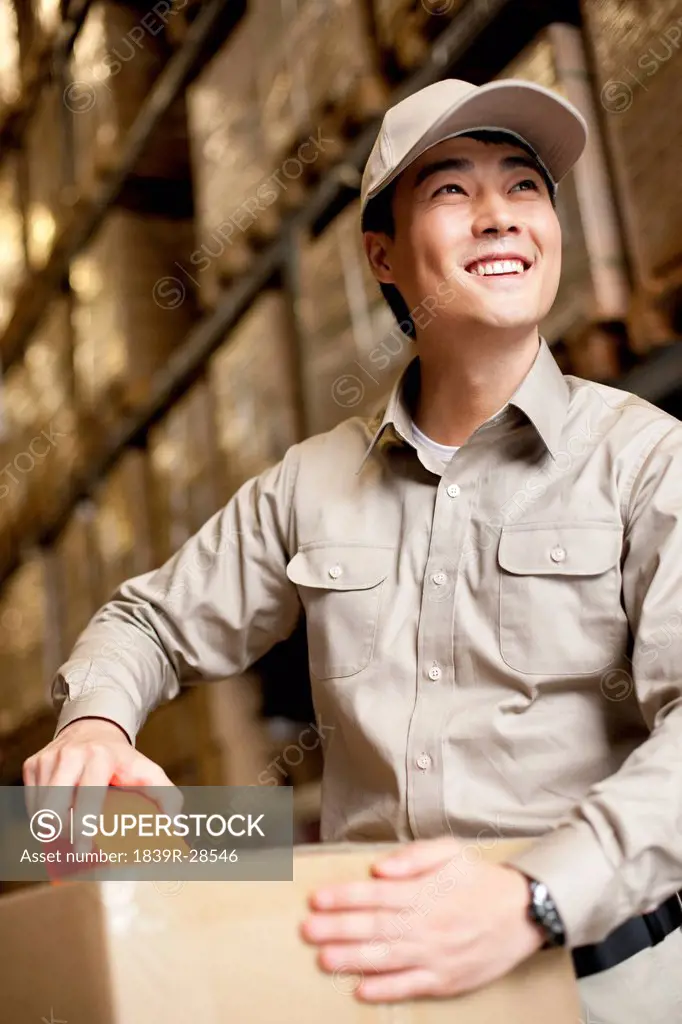 Male Chinese warehouse worker packing a box