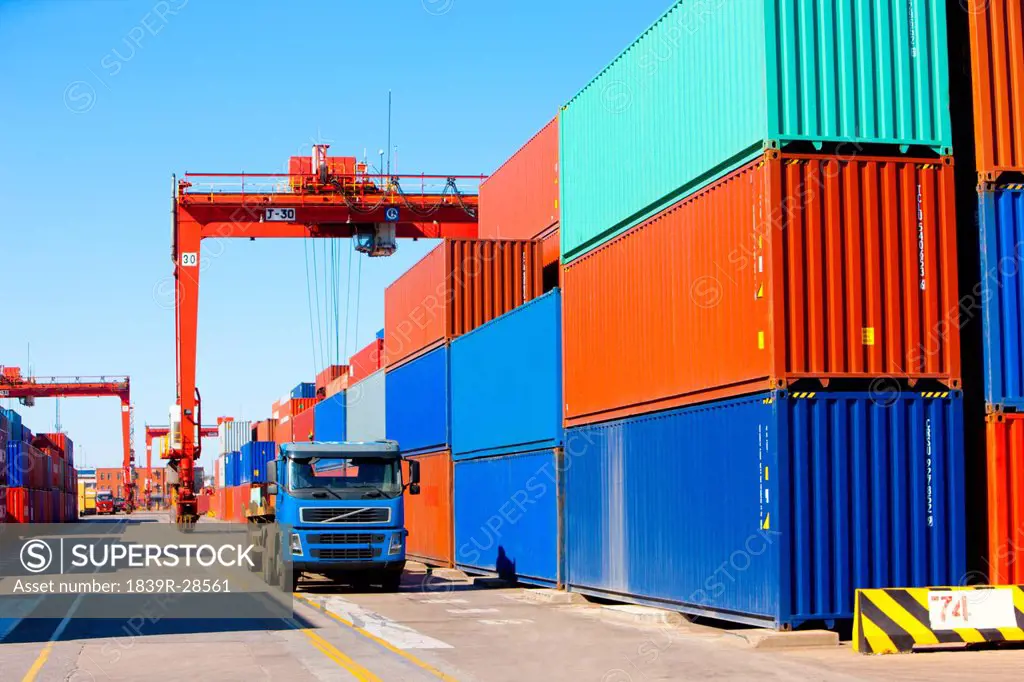 Cranes, trucks and cargo containers in shipping dock