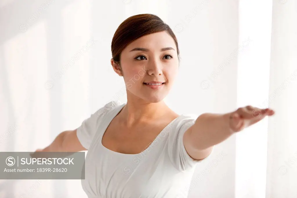 Young woman practicing yoga with arms outstretched