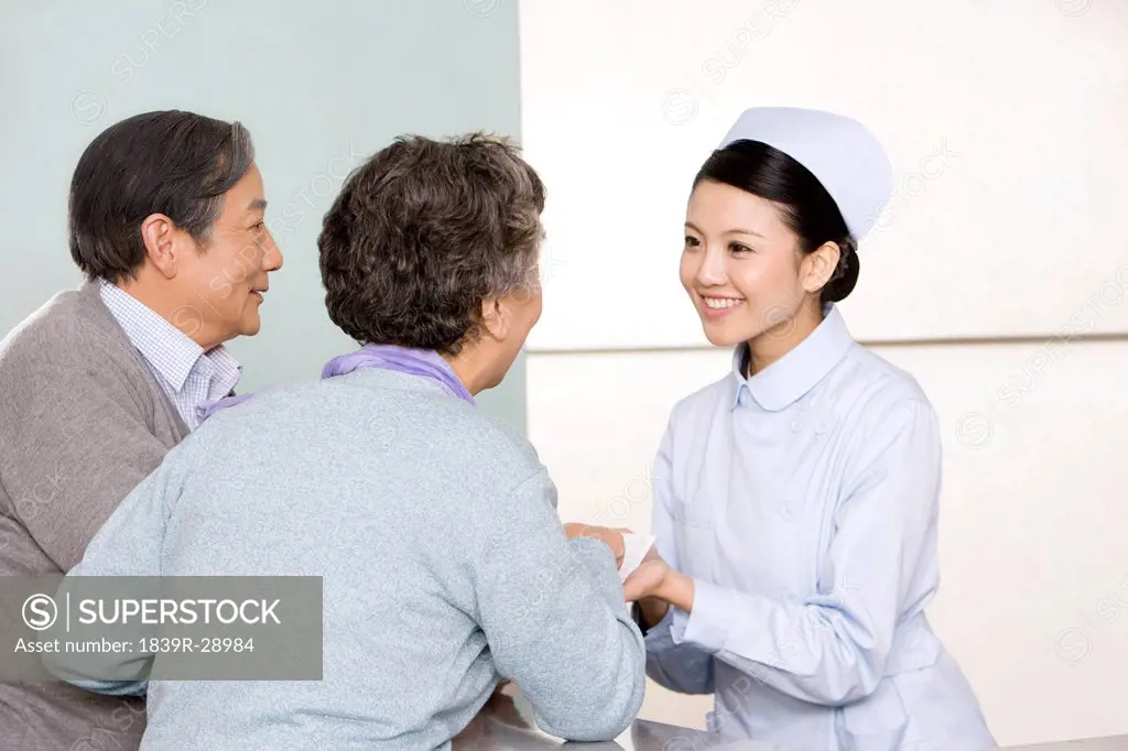 Young Nurse Helping Senior Couple at Nurses´ Station