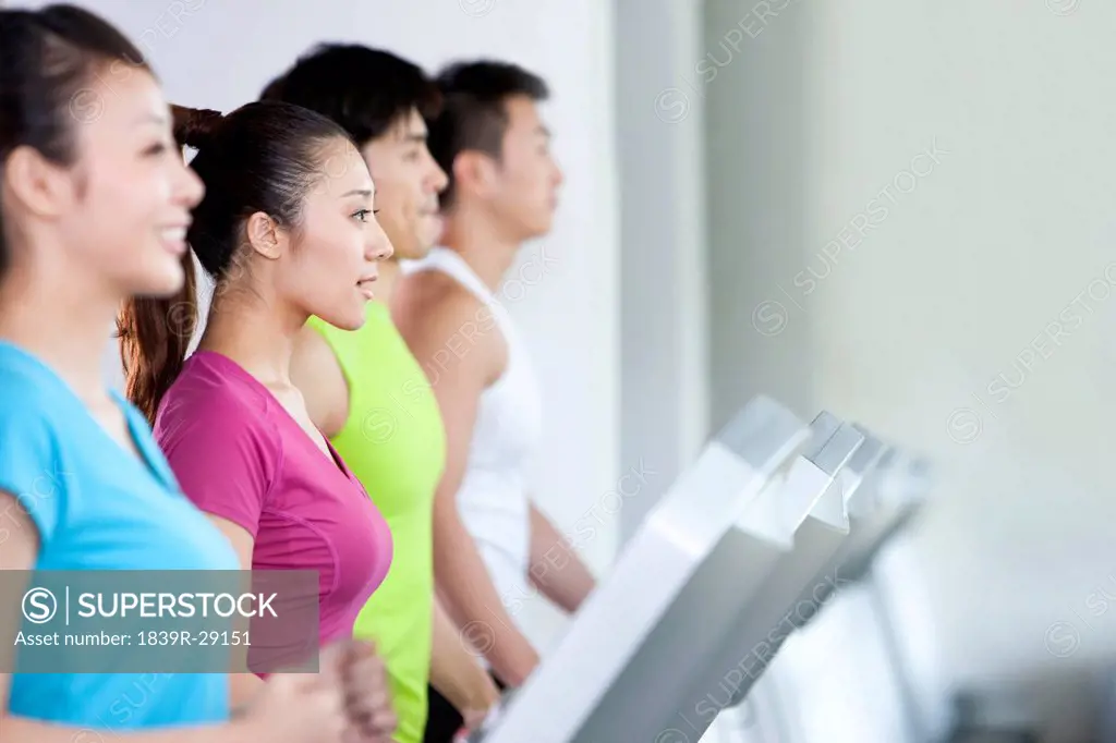 Four People Running on Treadmills