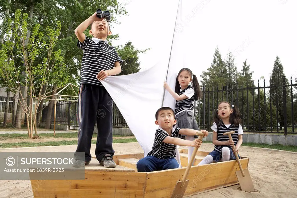 Young Children Seated In A Boat In A Sandpit
