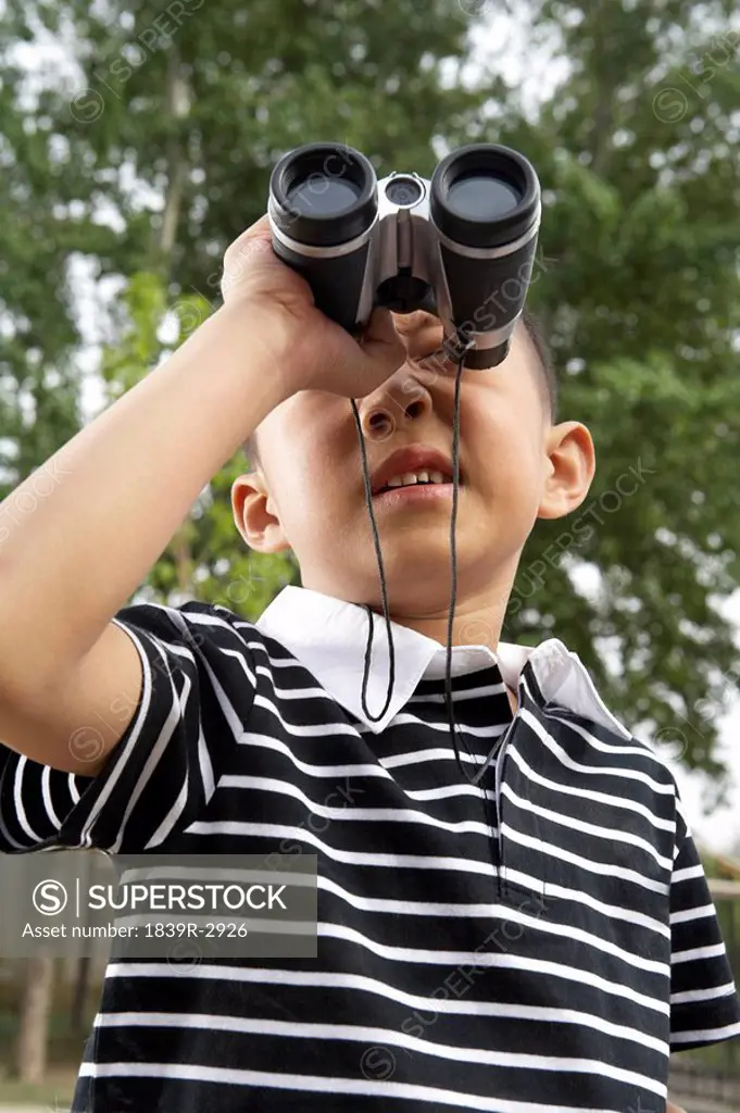Young Boy In A Sandpit With Binoculars