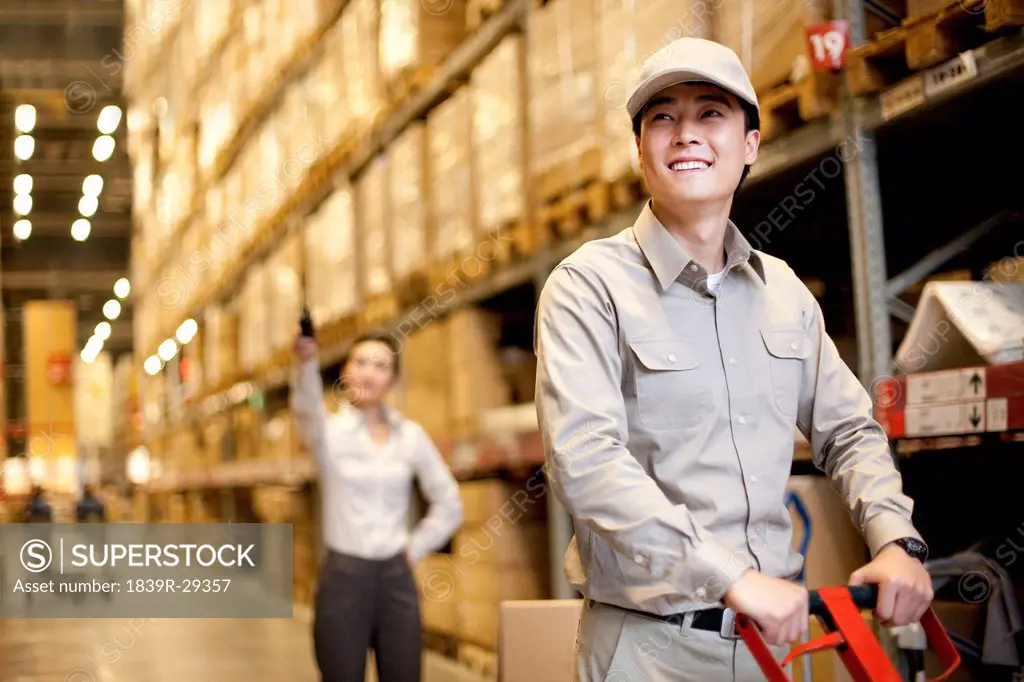 Male Chinese warehouse with Chinese businesswoman in the background
