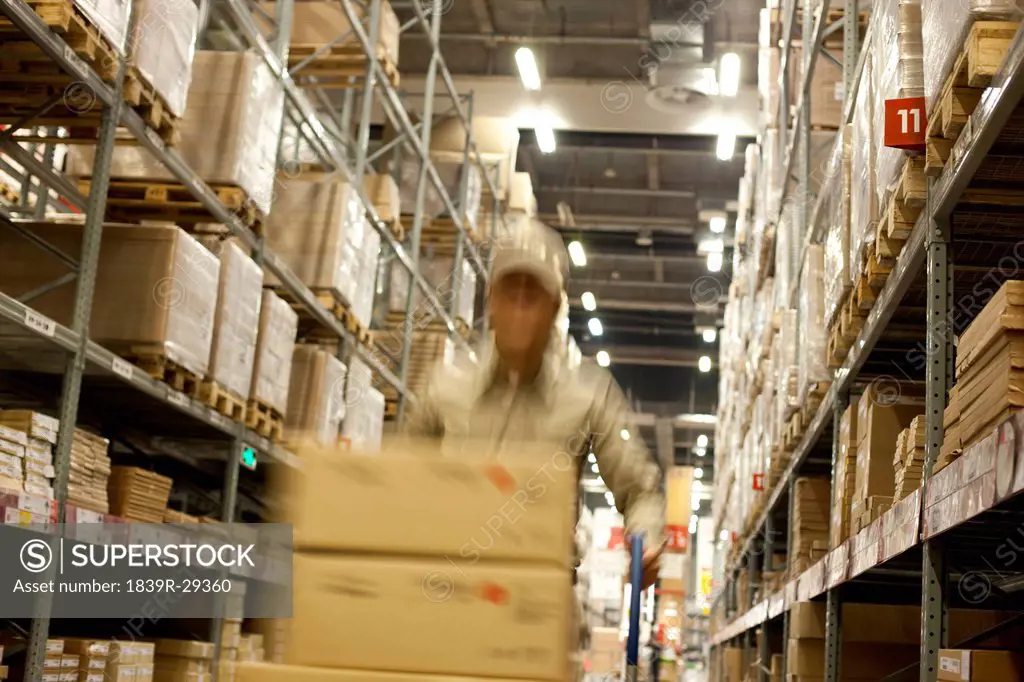 Blurred motion shot of Chinese warehouse worker pushing boxes