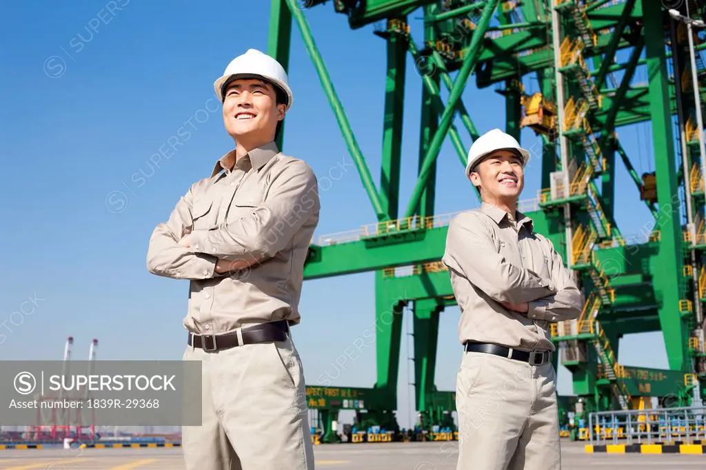 Male shipping workers on walkie talkies in a shipping dock