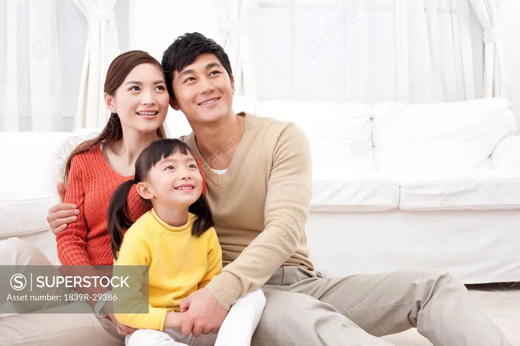 Happy young family sitting on carpet