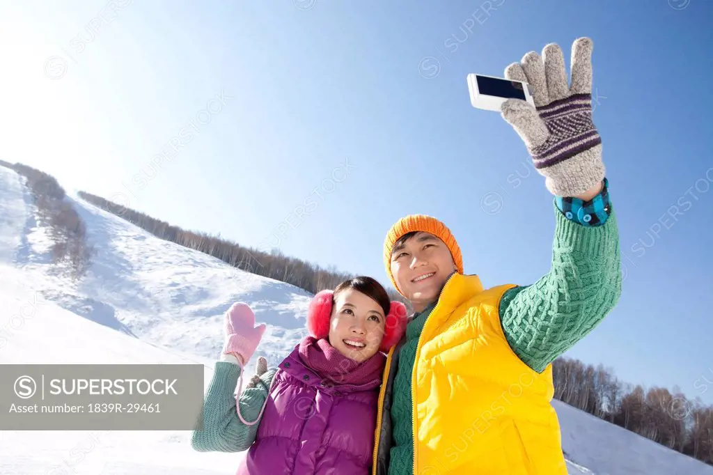 Happy young couple taking pictures in ski resort
