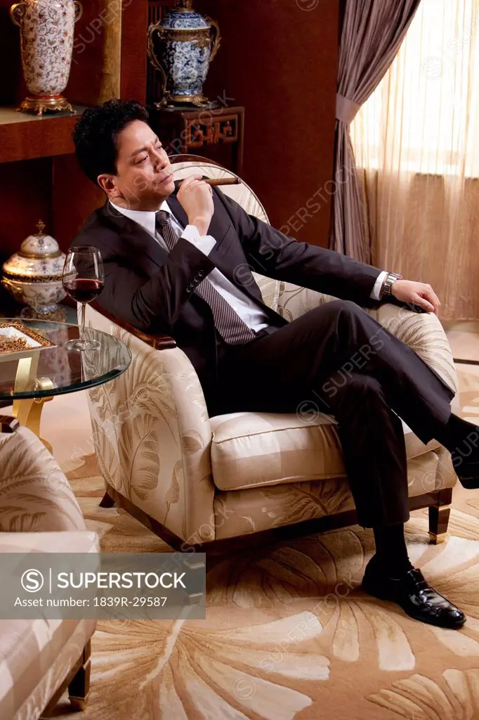 Mature businessman enjoying cigar and wine in a luxurious room