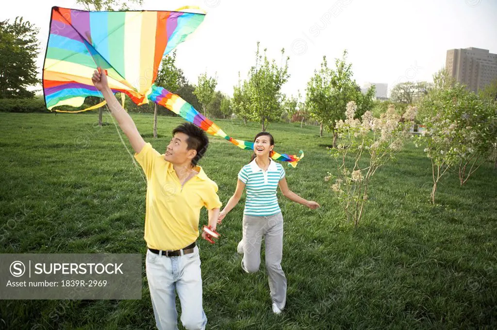 Young Couple Flying Kite In Park
