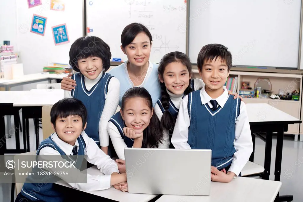 Students and teacher gathered around a computer in the classroom