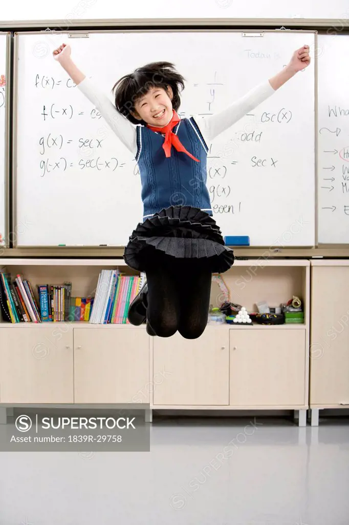Young student jumping in front of whiteboard