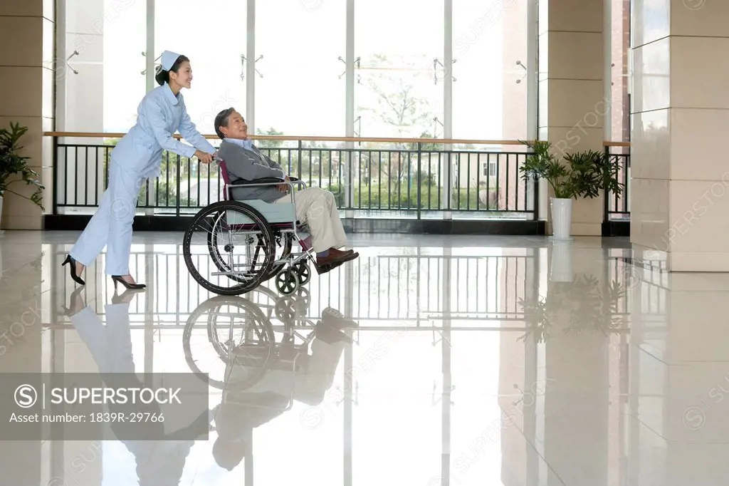 Nurse Pushes Senior Man in a Wheelchair