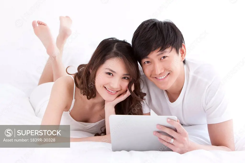 Young couple using digital tablet in bed