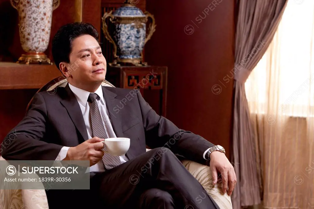 Mature businessman having coffee in a luxurious room