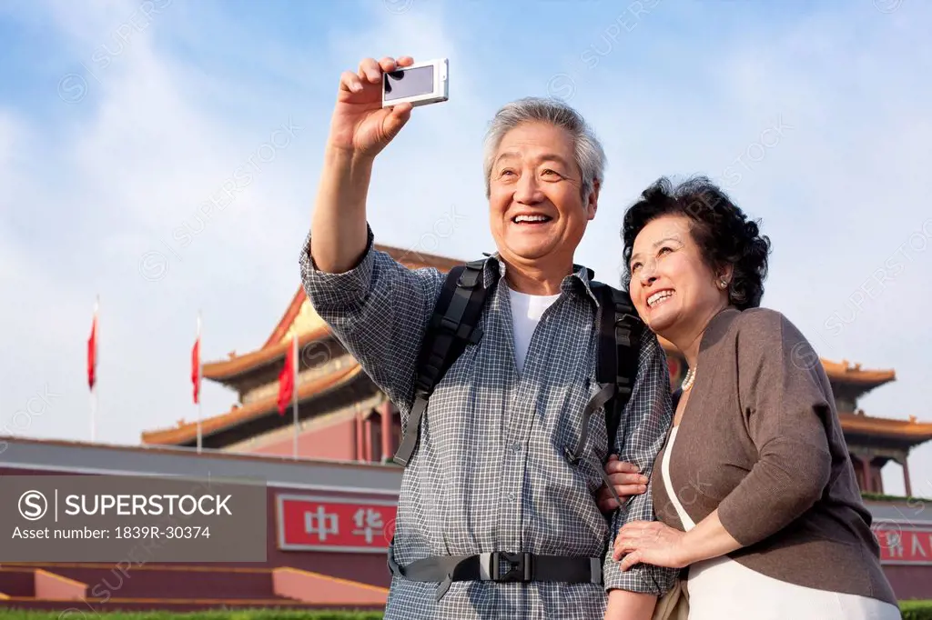 Senior couple photographing themselves at Tiananmen Square in Beijing, China