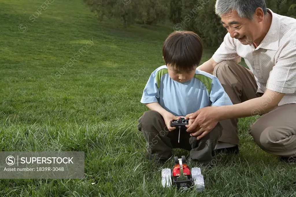 Grandfather And Grandson With A Remote Control Car In The Park