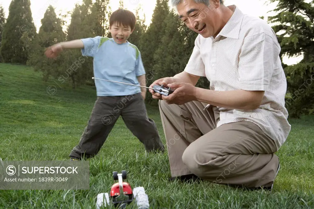 Grandfather And Grandson With A Remote Control Car In The Park