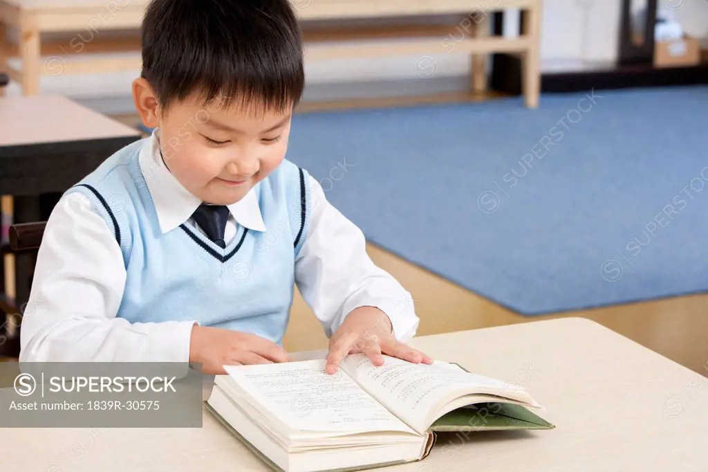 Young boy reading at his desk in a classroom
