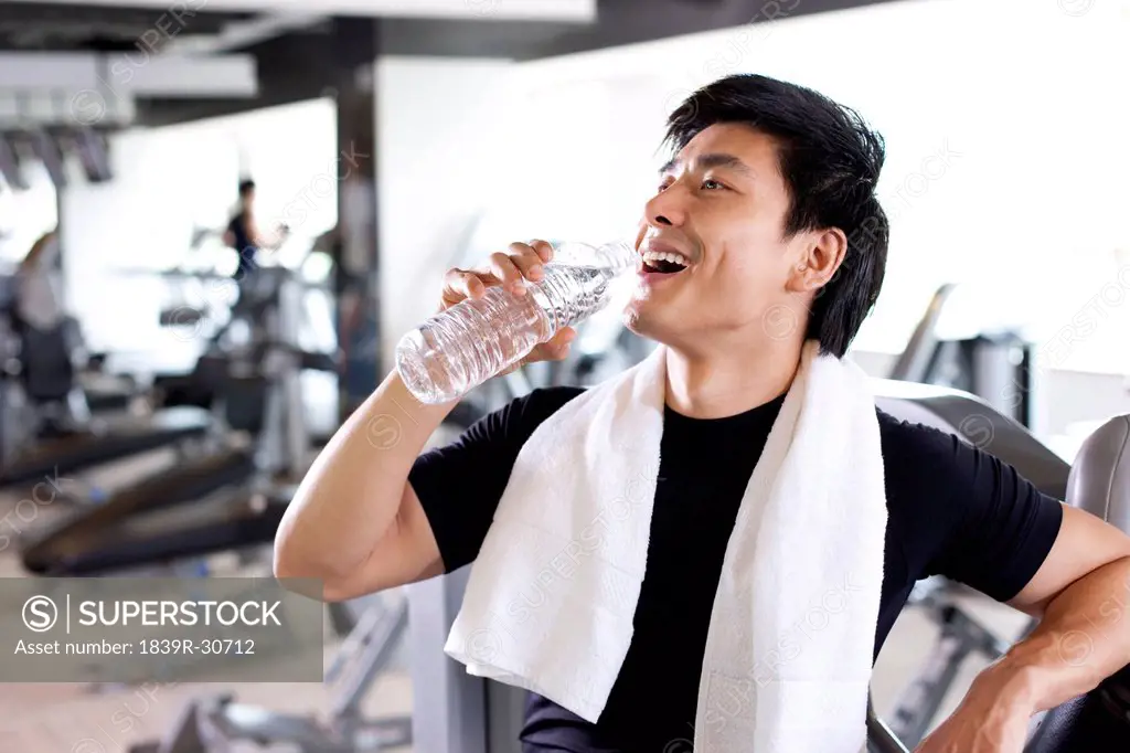 Young Man Drinking Water at Gym
