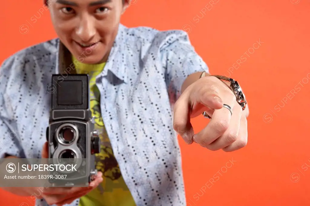 Young Man Holding Vintage Film Camera And Pointing