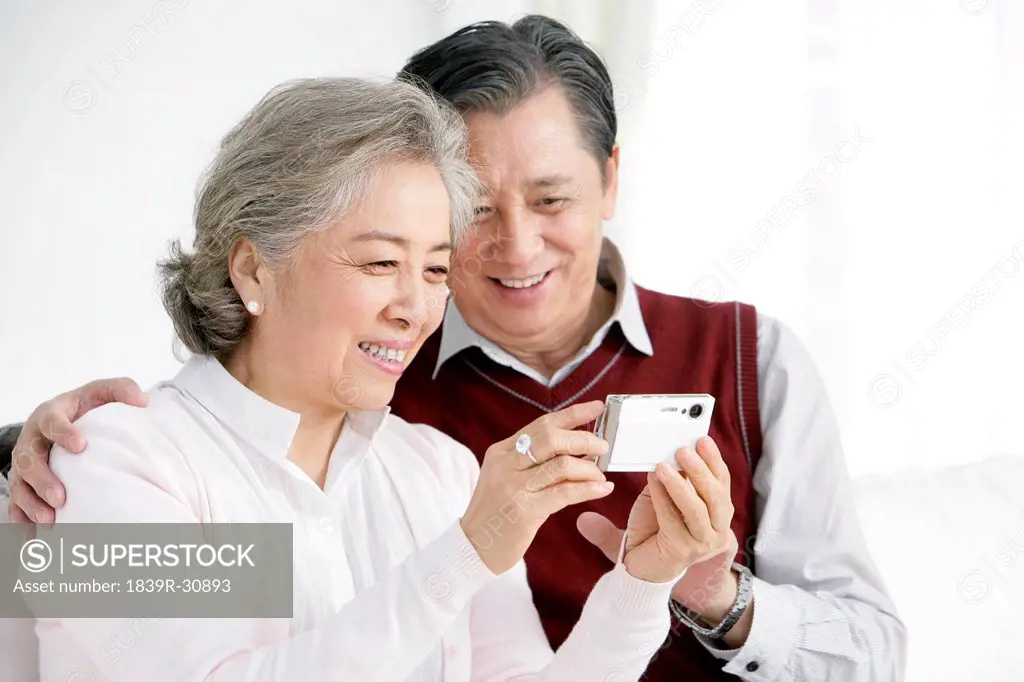 Senior Chinese couple looking at pictures in living room