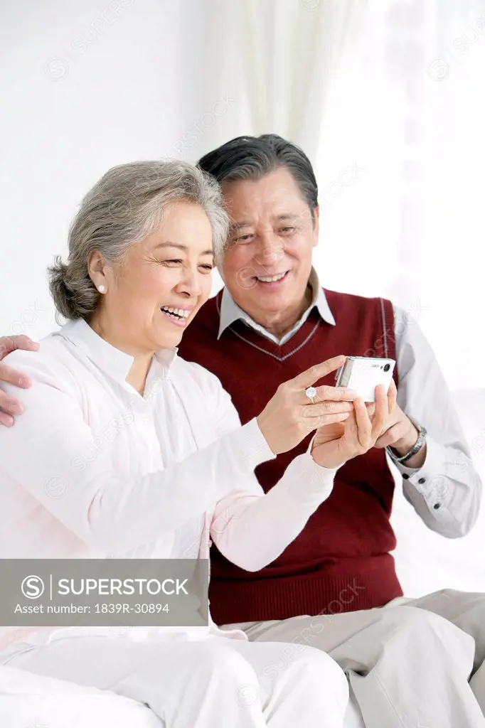 Senior Chinese couple looking at pictures in living room