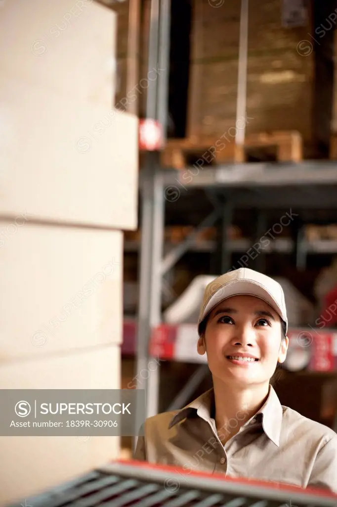 Female Chinese warehouse worker looking at boxes