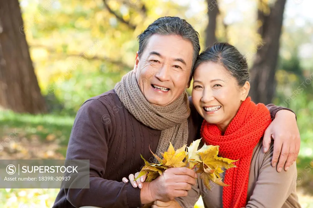 Senior couple collecting leaves in Autumn