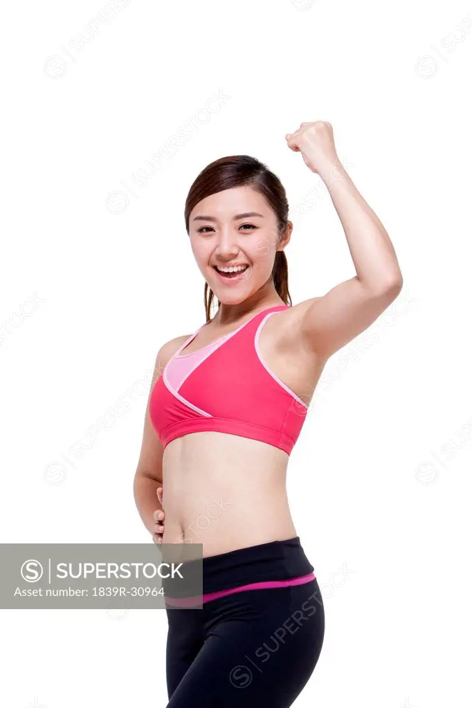 Young woman in sports clothing flexing her muscles