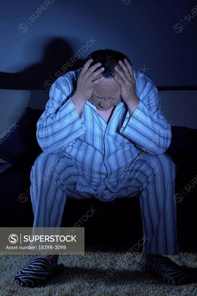 Man In Pajamas Sitting On Couch Watching Television
