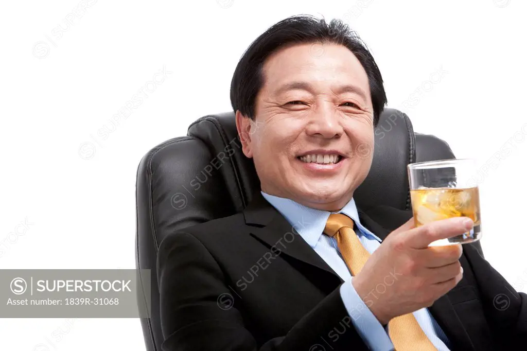 Senior businessman enjoying whiskey on director´s chair