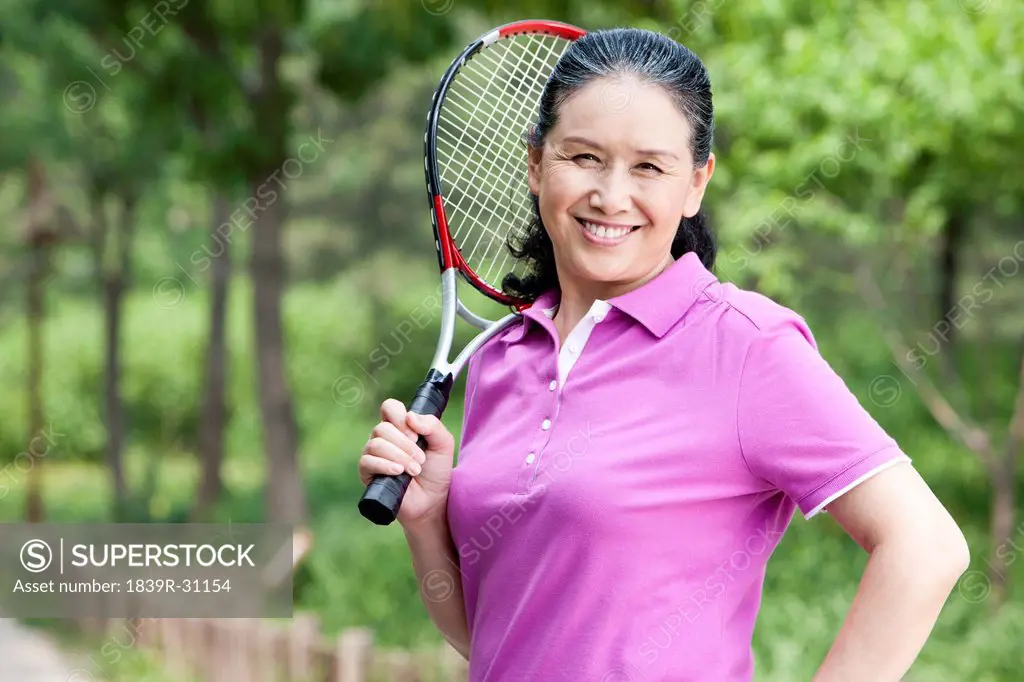 Senior woman playing tennis in park