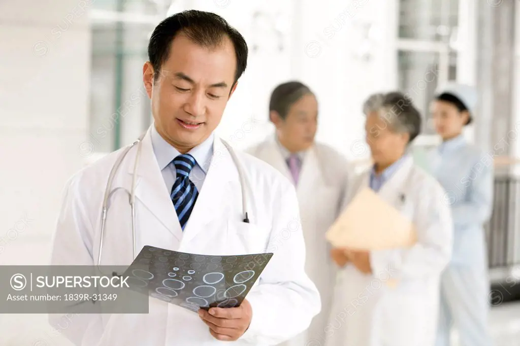 Doctor Looking at CAT Scan with Doctors and Nurse in Background