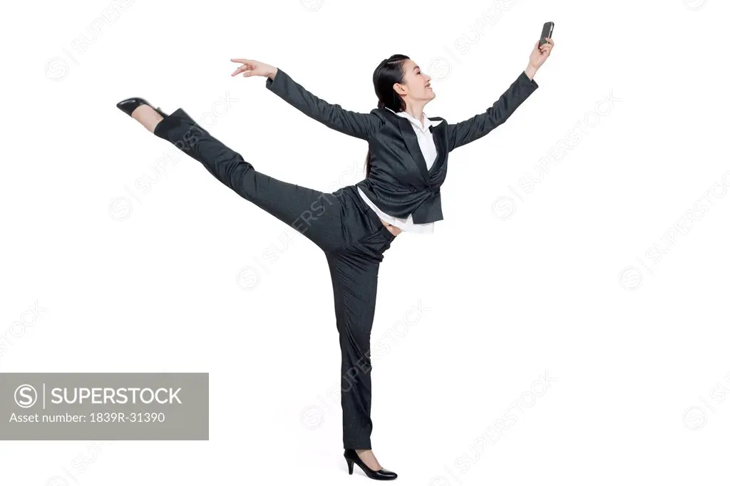 A dancing businesswoman holding a mobile phone