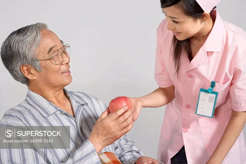 Nurse Giving An Apple To Man