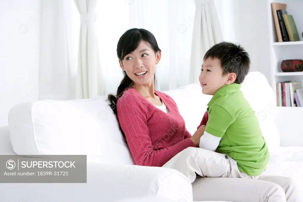 Chinese mother and son looking away on sofa