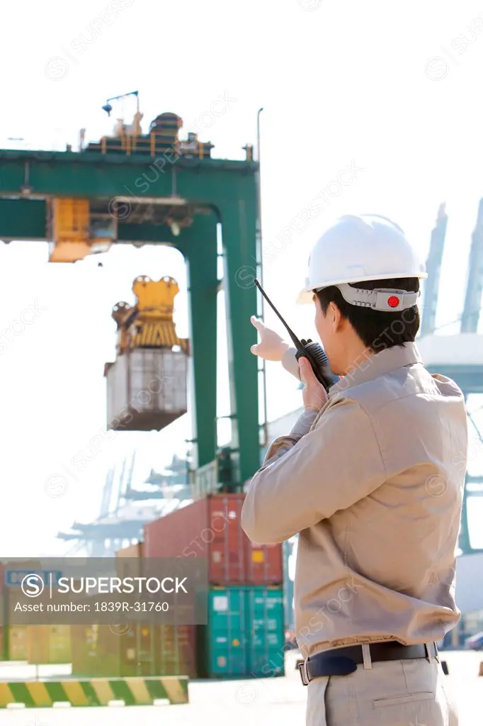 shipping industry worker directing cranes with his walkie_talkie