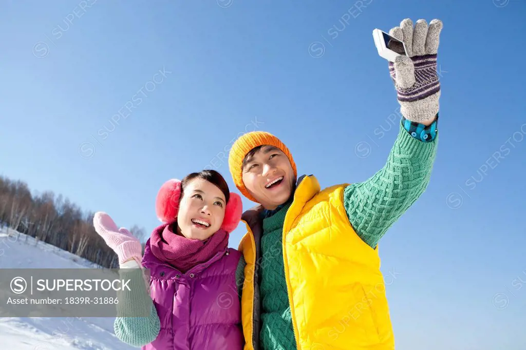 Happy young couple taking pictures in ski resort